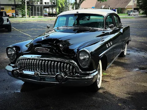 Classic black Buick sedan with a chrome grille and white roof parked after a detail