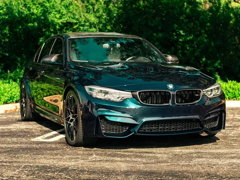 Dark teal BMW M3 sedan parked on a gravel driveway after a detail