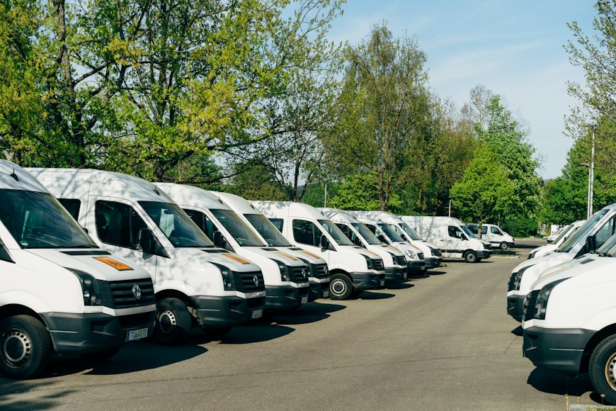 Row of white commercial vans parked in a lot