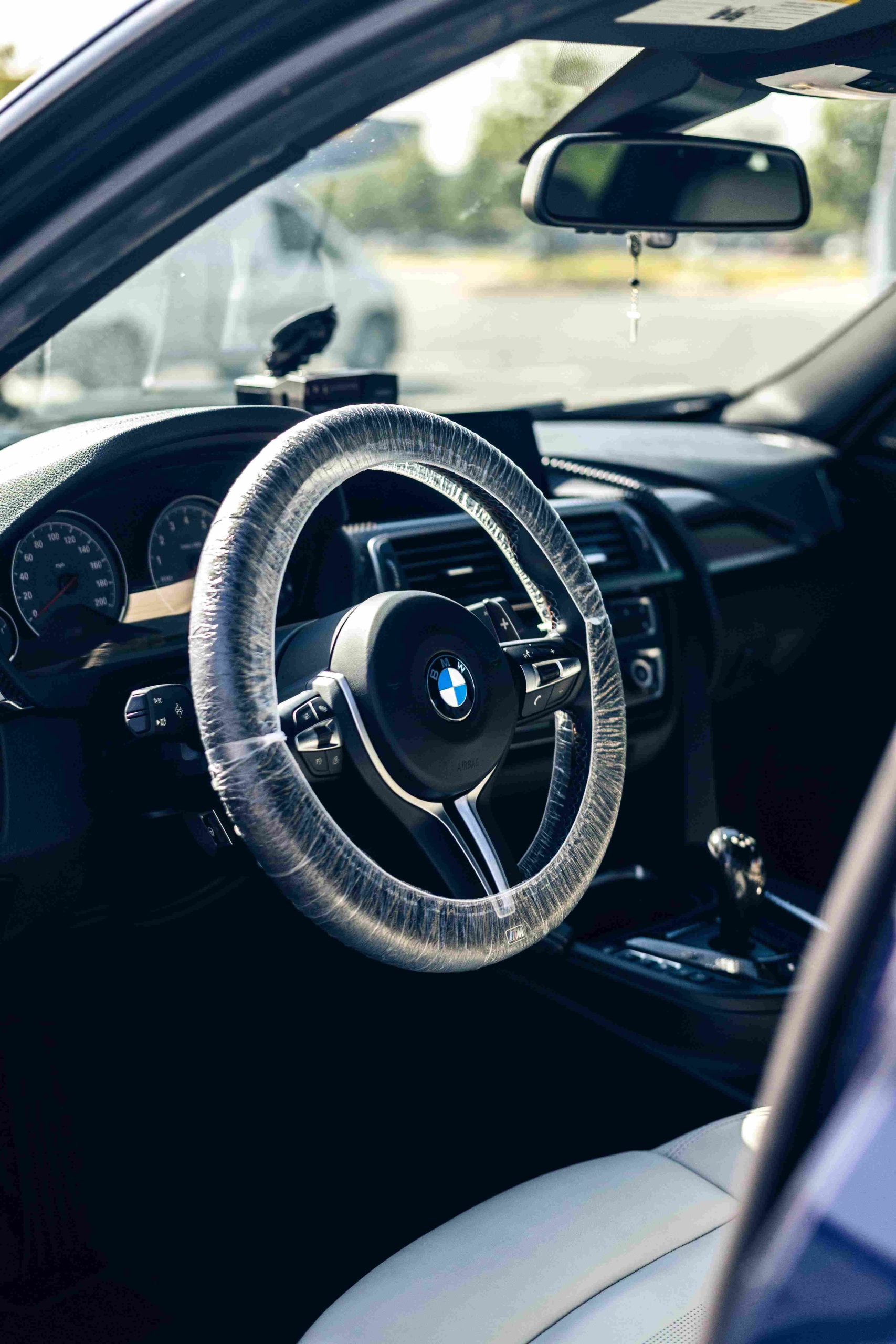 BMW cabin during an interior car detail, steering wheel wrapped in a protective cover