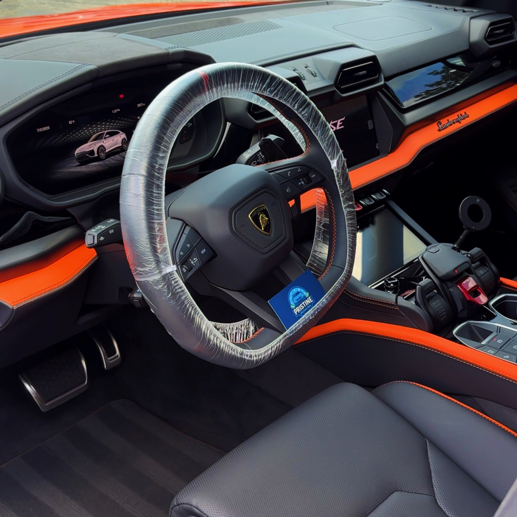 Lamborghini interior with orange trim during an interior detail, steering wheel wrapped in a protective cover