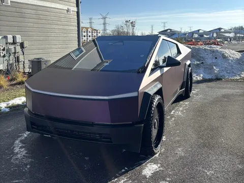 Tesla Cybertruck with an iridescent color-shift wrap parked in a driveway after a detail