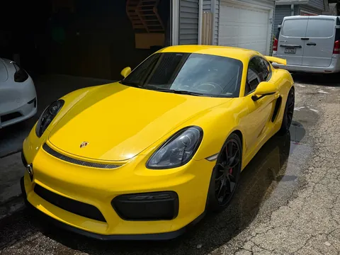 Yellow Porsche Cayman GT4 parked in a driveway after a mobile detail