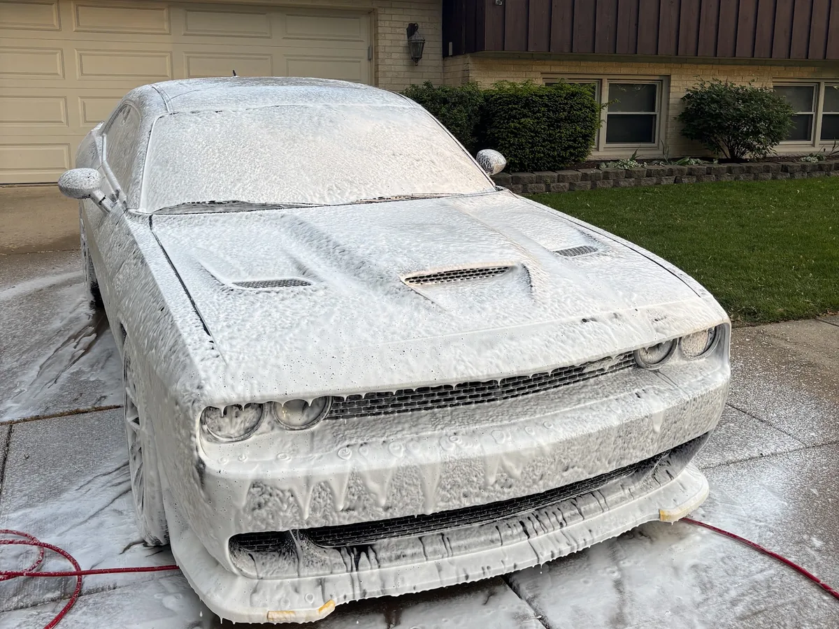 Dodge Challenger SRT covered in foam during a mobile wash in a customer's driveway